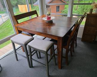 Awesome high top dining table with two wooden stools and a wooden bench.