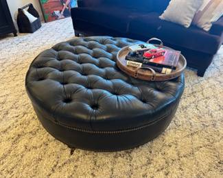 Large 4' circular tufted leather ottoman/coffee table with nailhead trim. Dark navy upon close inspection- but honestly we thought it was black for 2 weeks! Could pass for black if needed!