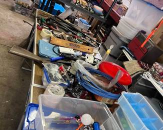 The garage tables are loaded with tools, products, crates, bins and somewhere under one of these tables are several four wheel garage dolly skates.