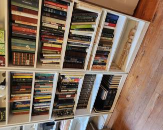 White bookshelves, stocked with items like Frank Lloyd Wright, textbooks. Fiction and non fiction