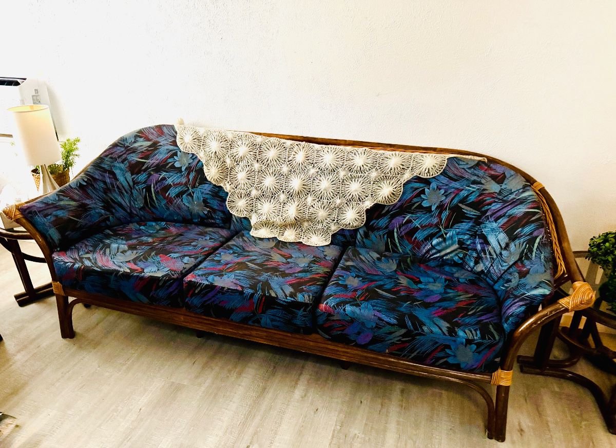 Rattan sofa with custom tropical print cushions and crocheted doily