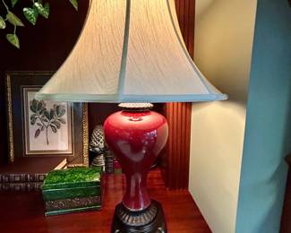 Red glazed ceramic urn-style table lamp with decorative base and silk-look shade