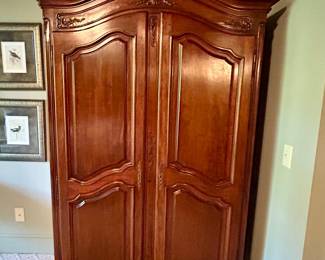 French Provincial-style carved cherry armoire with double paneled doors and cabriole feet