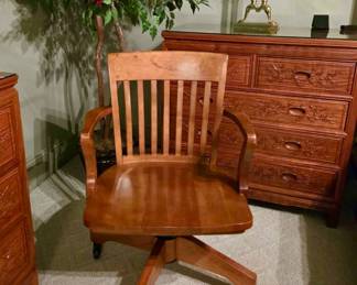 Wooden swivel desk chair with a slatted back, curved arms, and rolling base