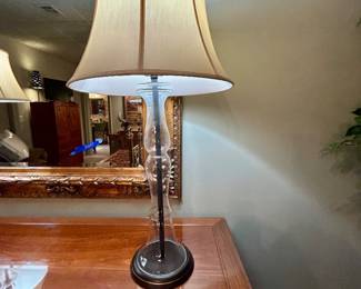 Elegant clear glass baluster-style table lamp with dark base and cream shade