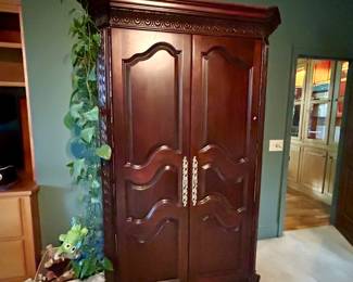 Dark wood wardrobe with carved trim, mirrored doors, interior shelving and three drawers