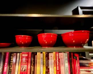 Three red Le Creuset nesting bowls and a collection of cookbooks