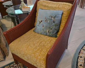 Wicker armchair with gold cushions and hummingbird pillow