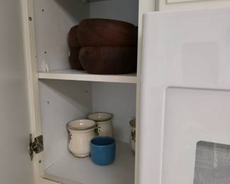 Kitchen cabinet with brown stoneware bowls and ceramic canisters