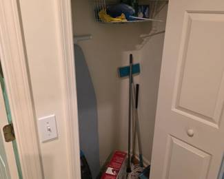 Utility closet with ironing board, mops, brooms and supplies