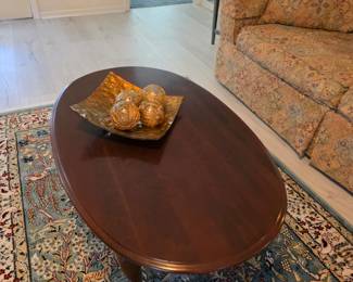 Oval mahogany coffee table with decorative bowl and orbs