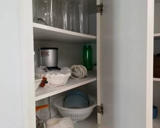 Kitchen cabinet with drinking glasses, colander and kitchen tools