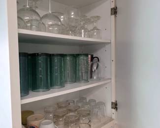 Kitchen cabinet with stemware, teal tumblers, mugs and glasses