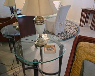Pair of round glass-top end tables with brass and cream lamps
