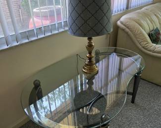 Oval glass-top end table with brass lamp, patterned shade