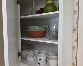 Kitchen cabinet with green vase, glass mixing bowls, white ramekins