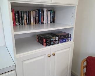 White built-in cabinet with open shelves, books and puzzles
