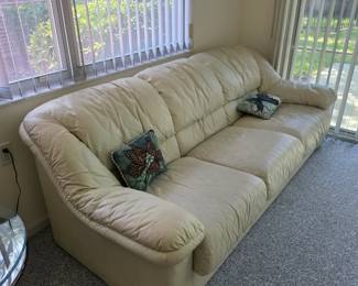 Cream leather sofa with rolled arms and accent pillows