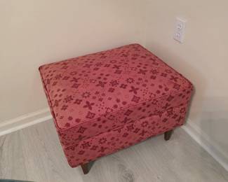 Upholstered ottoman in red floral fabric