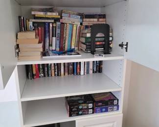 Built-in cabinet interior shelves with paperback books, puzzles