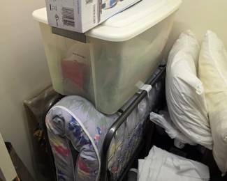 Closet with folding guest cot, storage bin, pillows and bedding