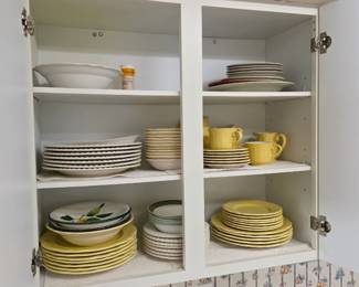 Kitchen cabinet with dinnerware sets: yellow, white and floral plates