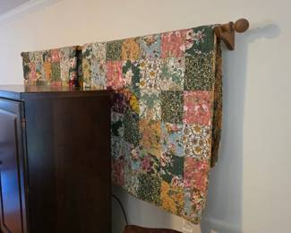 Floral patchwork quilt hung on wooden quilt rod