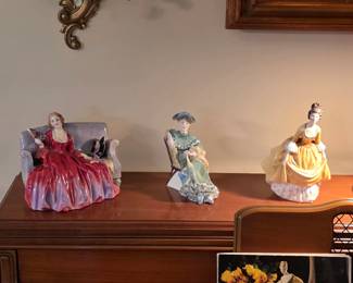 Royal Doulton porcelain figurines displayed atop the piano, featuring seated and standing ladies in colorful gowns.