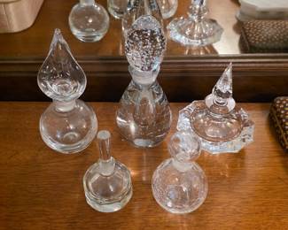 Decorative glass perfume bottles with assorted shapes, faceted details and glass stoppers.
