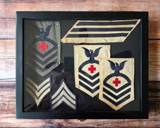 Vintage U.S. Navy rating patches and service stripes presented together in a framed display.