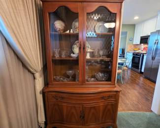 Traditional wood china cabinet with glass-front upper display and enclosed lower storage.