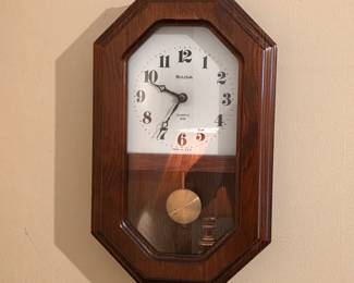 Bulova quartz pendulum wall clock with wood case and easy-to-read Arabic numerals.