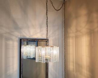 Vintage hanging light with textured glass panels, displayed beside a tall decorative wall mirror