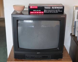 Vintage CRT television with a boxed VHS video cassette rewinder.