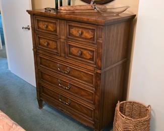 Vintage tall wood chest of drawers with decorative drawer fronts and traditional metal pulls.