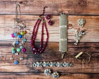 Vintage costume jewelry assortment featuring colorful necklaces, rhinestone bracelets and brooches.