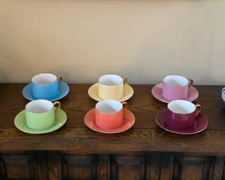 Six colorful cups and matching saucers in blue, yellow, pink, green, coral and burgundy.