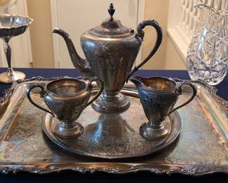 Ornate silverplate tea service with lidded pot, creamer, sugar bowl and handled serving tray.