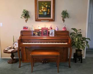 Kranich & Bach upright piano with matching bench, surrounded by porcelain figurines and framed floral artwork