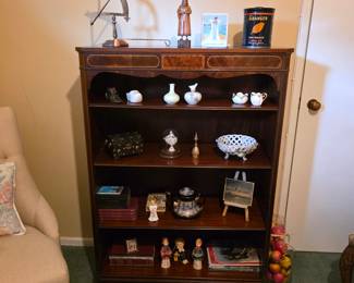 Traditional wood display bookcase with decorative trim, porcelain miniatures, books and small collectibles.