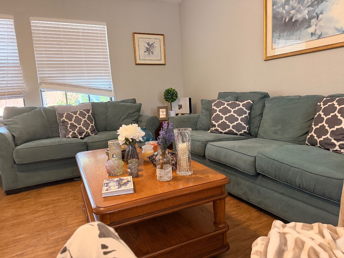 Living room with slate blue sofa and loveseat and wood coffee table at a Euless estate sale