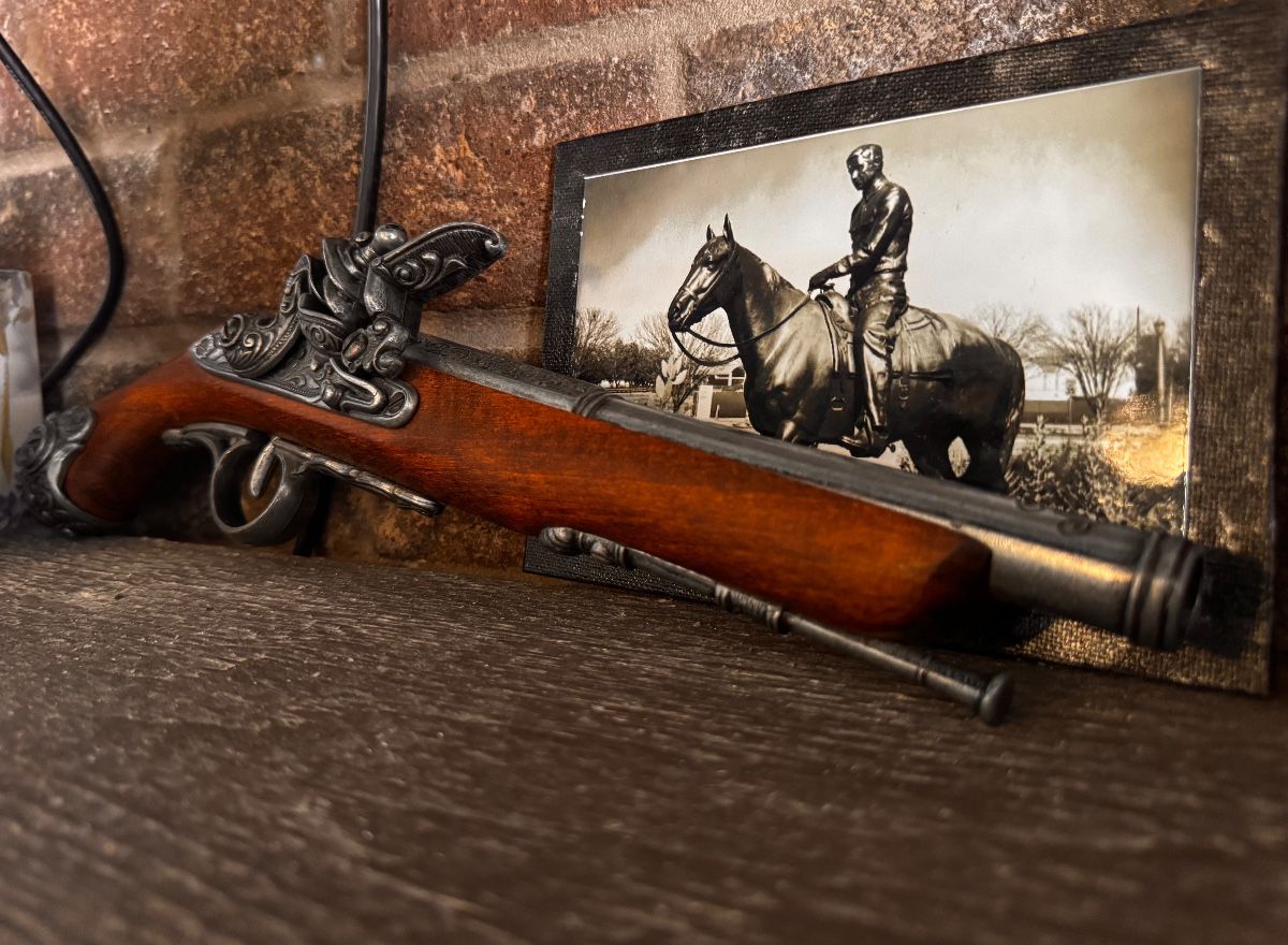 Decorative flintlock pistol replica with framed western horse and rider print
