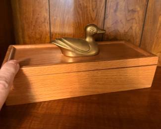 Stately wooden box with hinged top adorned with a brass duck