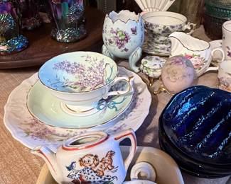 Assortment of vintage teacups and saucers, floral china, miniature tea pieces, creamers, decorative ceramics, and colorful iridescent carnival glass pitchers and tumblers