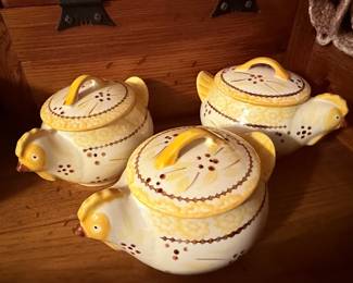 Stoneware Chicken Soup Tureen Collection – Vintage stoneware serving collection featuring a chicken-shaped soup tureen with matching lid and metal warming stand, along with coordinating covered soup bowls. Decorated with a hand-painted country chicken motif in warm yellow and brown tones. A charming set for serving soups, stews, or displaying in a farmhouse kitchen.