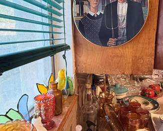 Collector plate featuring Grant Wood’s iconic “American Gothic” image of a farmer and woman posed in front of a farmhouse.