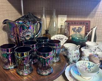Iridescent Carnival Glass Pitcher & Tumbler Set – Vintage-style carnival glass beverage set featuring a large pitcher with six matching tumblers. Each piece has a richly embossed floral design with a multicolor iridescent finish. A striking set for serving, display, or a carnival glass collection.