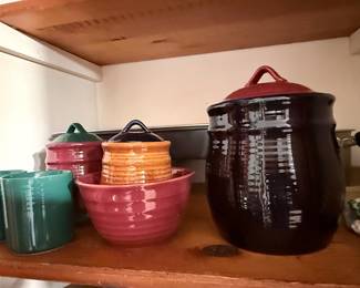 Vintage Stoneware Kitchen Collection – Assortment of colorful glazed stoneware including ribbed canisters with lids, mixing/serving bowls, and coordinating mugs in deep green, burgundy, orange, and brown. Great for kitchen storage, serving, or rustic décor.
