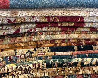 Assorted folded area rugs featuring traditional, tribal and pictorial patterns
