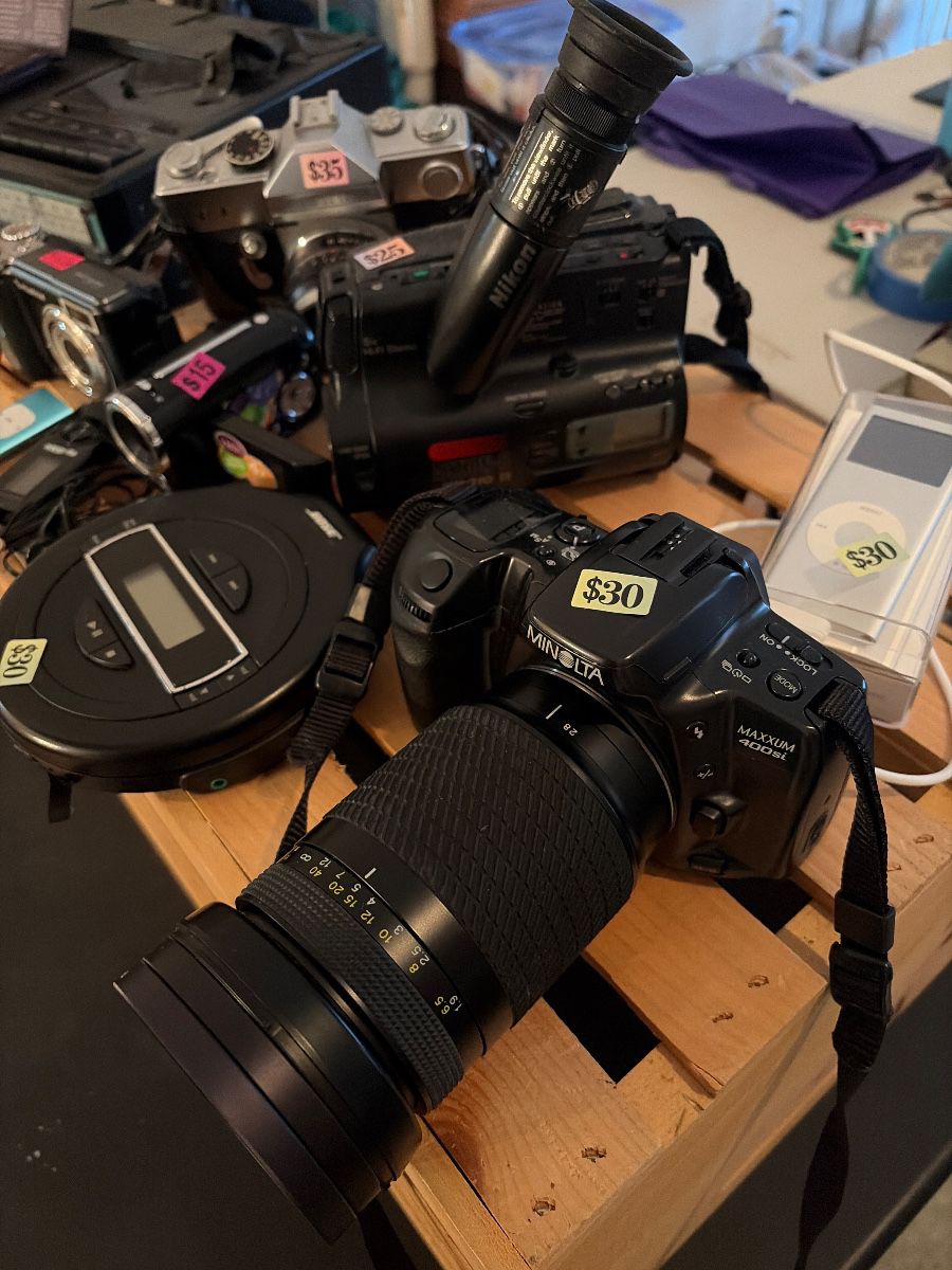 1. Apple iPod Nano (1st Generation) 2. Unisonic XL-985 Portable TV/Radio/Cassette Recorder & Quartz Clock 3. Bose PM-1 Portable CD Player 4. Petri FT 35mm SLR Camera 5. Minolta Maxxum 400si 35mm SLR Film Camera 6. Fujifilm FinePix E900 Digital Camera 7. Generic 3.1 MP Digital Video Camcorder 8. Nikon Action-8 VN-310 8mm Video Camcorder 9. Franklin Bookman Electronic Holy Bible (KJB-440)